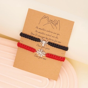 Detail of red and black woven friendship bracelets with spider and web charms on card