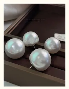 Macro detail of high-luster white oversized pearl earrings on a dark textured background