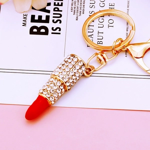 Detailed close-up of a sparkling rhinestone lipstick-shaped keychain with red enamel and gold metal