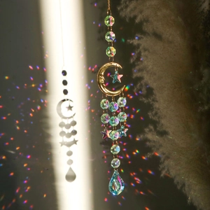 Hanging crystal suncatcher with golden moon stars reflecting rainbows on wall