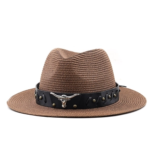 Close-up of woven straw cowboy hat with black leather band and silver bull head detail