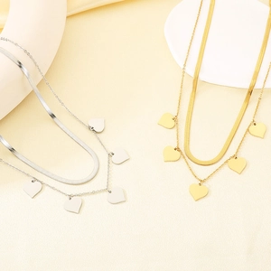 Détail de colliers doubles en acier inoxydable avec pendentifs en cœur or et argent