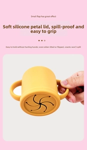 Detail of food-grade yellow silicone baby snack cup with petal lid and double handles