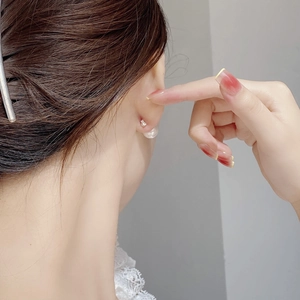 Close-up of 925 sterling silver pearl stud earrings worn by model for elegant style