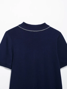 Détail d'un haut en maille bleu marine avec bordure festonnée blanche sur le col