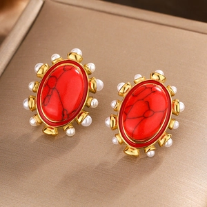 Macro shot of oval vintage earrings with red turquoise center and white pearl halo