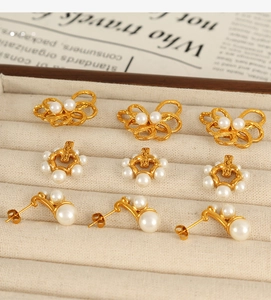 Dettaglio di un set di orecchini di perle dorate su un vassoio portagioie beige