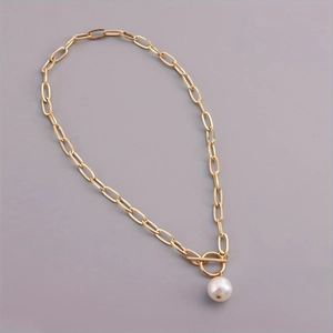 Detail of golden paperclip chain necklace with pearl pendant and toggle clasp closure