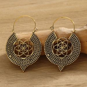 Close-up of bohemian gold drop earrings with turquoise on a natural wooden branch