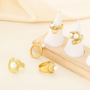 Collection of textured gold geometric rings with white and champagne pearls in detailed view