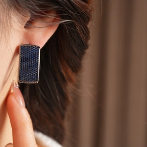 Close-up of vintage blue zircon square drop earrings worn by a model in warm light