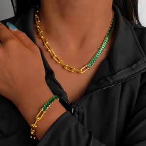 Detailed view of U-shaped horseshoe chain and green zircon stones on necklace and bracelet