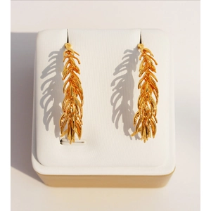 Elegant gold wheat leaf drop earrings displayed on a white jewelry stand with soft shadows