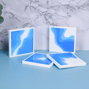 Detailed view of four square resin coasters with blue gradient ocean layers and white base