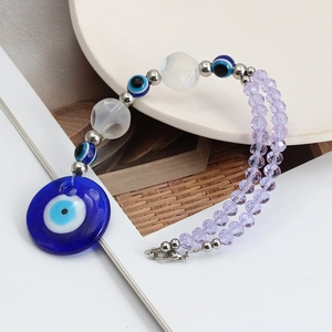 Handmade Evil Eye keychain with blue beads and purple crystals on white background