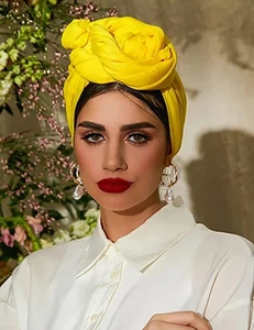 Detail of a bright yellow textured headwrap with handmade pleats worn by a model
