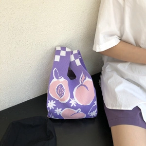 Detail of purple knitted tote bag with peach patterns and checkered handles