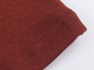 Détail de la texture en maille rouge brique et des coutures de finition de qualité