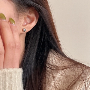 Close-up of a minimalist silver-grey pearl stud earring worn on a model's ear