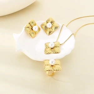 Detail of gold jewelry set with pearl inlays and diamond texture on a shell tray