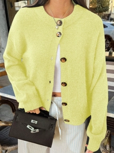 Détail d'un cardigan en maille jaune avec col rond et fermeture à boutons classique