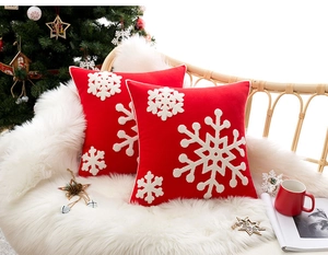Close-up of red Christmas pillow covers with white snowflake embroidery in a cozy setting