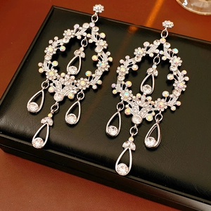 Detailed shot of silver drop earrings with rhinestones on a black leather jewelry box