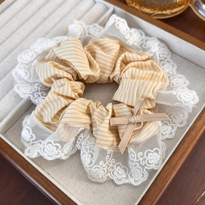 Close-up of beige plaid scrunchie with white lace trim and small bow detail