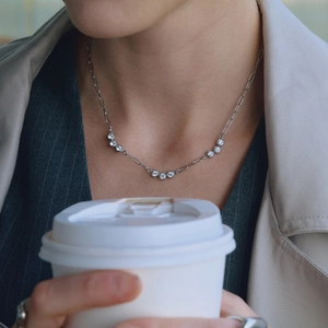 Detail of silver paperclip chain necklace with round zircons on professional model