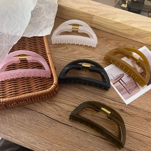 Five large hollow hair claws in neutral colors on a natural wooden and rattan background