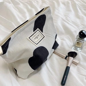 Detailed shot of the cow print corduroy makeup bag with PLEASANT TIME woven label