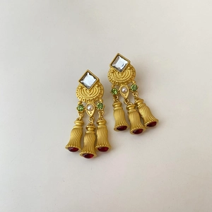 Close-up of vintage gold earrings with green crystals and red bell-shaped glass charms