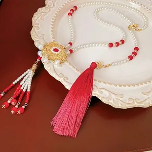 Elegant Chinese style pearl tassel necklace with red glaze lock pendant on a ceramic plate