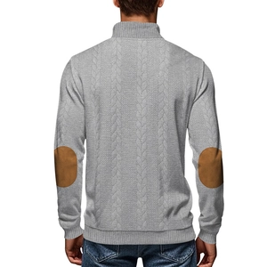 Detail view of grey knit sweater showing brown round elbow patches and cable texture