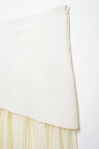 Close-up of white woven bodice with beige pleated mesh skirt and invisible side zipper