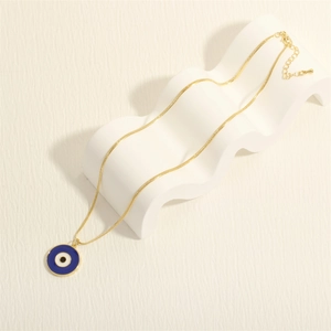 Detail of 18K gold plated snake chain with blue evil eye enamel pendant on a white stand