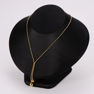 Minimalist gold bean Y-shaped beaded necklace shown on a black mannequin display