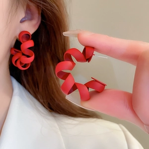 Detail view of red matte geometric spiral earrings featuring silver needles and frosted finish