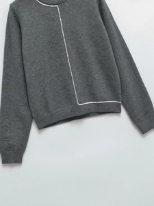 Detail showing grey knit sweater with ribbed neckline and unique white geometric line