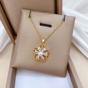 Close-up of golden hollow flower necklace with white pearl and sparkling crystals in a gift box