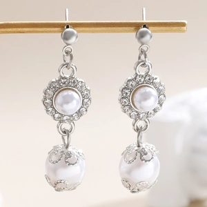 Dettaglio ravvicinato di orecchini vintage in argento con perle e lavorazione filigrana