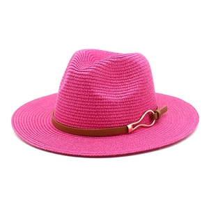 Detail of a bright magenta straw fedora with a brown leather band and gold buckle
