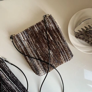 Detailed macro view of vintage tweed fabric texture and black slim strap on the crossbody bag