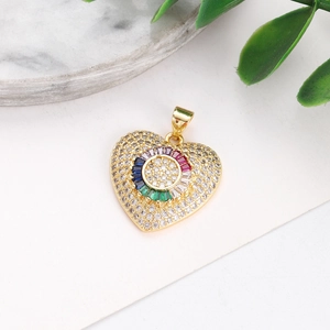 Detail shot of heart-shaped gold pendant with colorful crystals on marble background