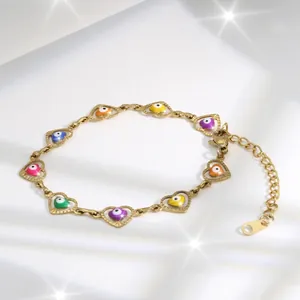 Detail of golden heart bracelet with multi-colored evil eye beads on white silk fabric