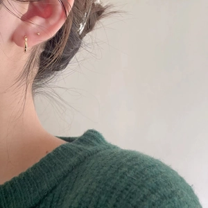 Nahaufnahme eines Models mit goldenem Creolen-Ohrring und passendem Goldstecker