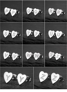 Macro shot of silver heart-shaped stainless steel earrings featuring engraved letters P-Z