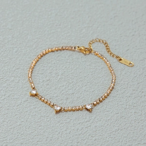 Elegant gold stainless steel tennis bracelet featuring three sparkling heart-shaped zircons
