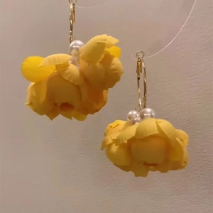Detail of yellow fabric flower earrings with white faux pearl centers and gold metal hoops