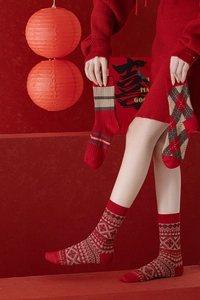 Détails de chaussettes en laine rouge avec motifs géométriques et flocons de neige